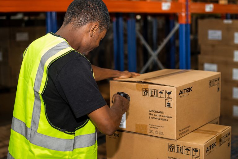 Opérateur logistique scannant un colis lors du contrôle des commandes.